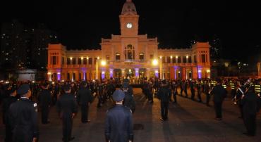 Foto noturna na praça da estação, com o prédio do Museu de Artes e Ofícios ao fundo e guardas municipais enfileirados