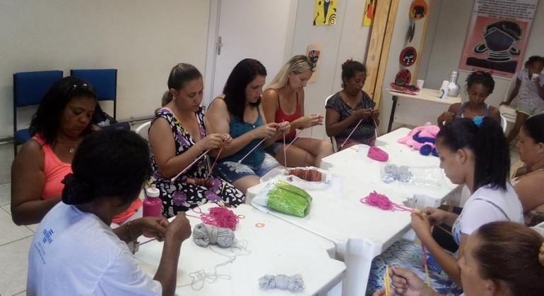 Cerca de nova mulheres fazem oficina de crochê.