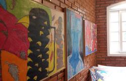 Três quadros coloridos expostos na parede de uma sala. 