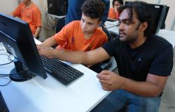 Instrutor ensina aluno em curso de informática no projeto “A Hora do Código”