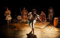 Mulher negra com tranças no cabelo dança. Ao fundo, três mulheres negras com instrumentos musicais tocam em cenário com inspiração africana. Peça Eras, do Coletivo Negras Autoras