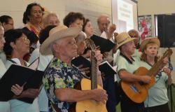 Grupo de mais de dez idosos canta e toca instrumentos no CAC Barreiro. 