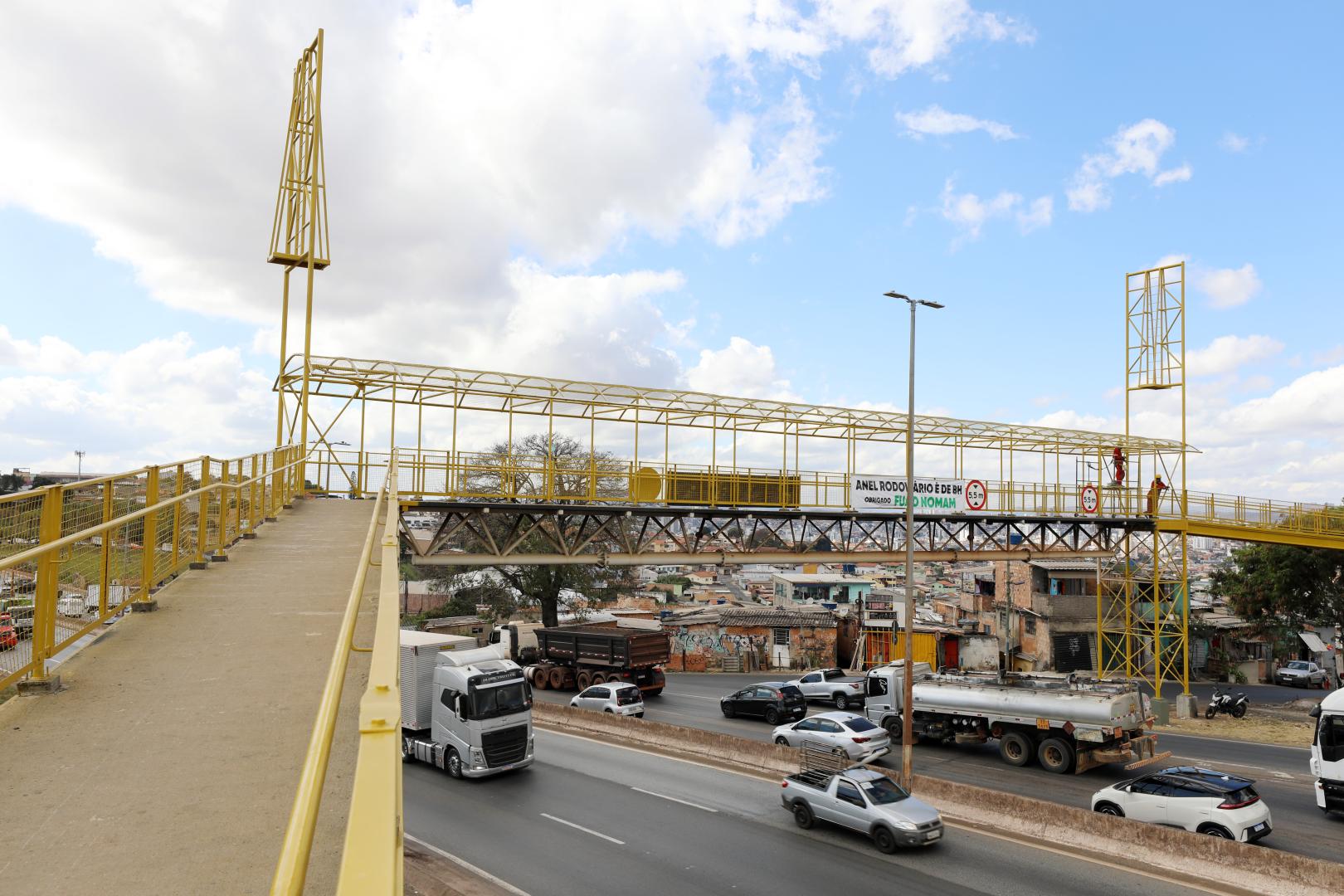 Carros e caminhões passando pelo Novo anel, abaixo da passarela de pedestres.