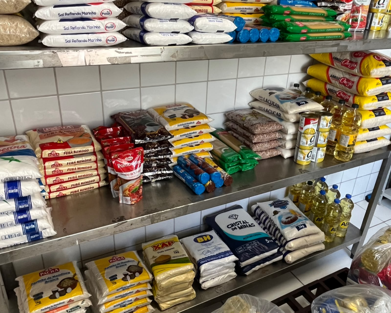 Donativos serão arrecadados no Arraial de Belô para reforçar o Banco de Alimentos da PBH prateleiras de metal com diversos sacos de alimentos empilhados