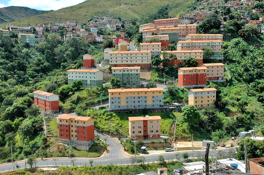 Inscrições abertas para palestra gratuita sobre urbanização, habitação e mudanças climáticas em BH Conjuntos habitacionais do Aglomerado da Serra, em Belo Horizonte, com prédios cloloridos cercados de mata verde.