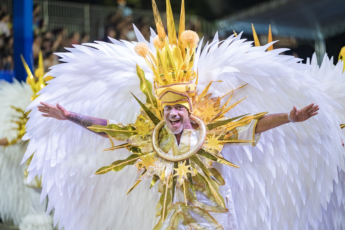 Integrante do Bloco Caricato Estivadores do Havaí posa com fantasia alegórica em tons de amarelo e branco durante o Carnaval de Belo Horizonte.