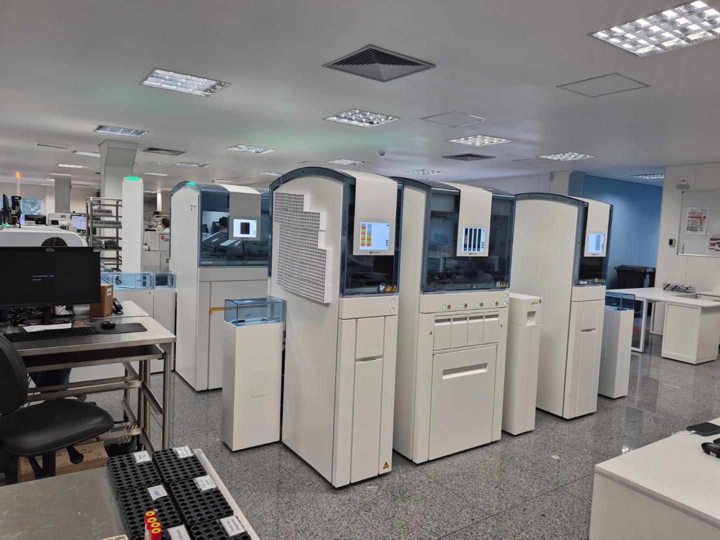 Inovação no SUS-BH: laboratório municipal adota tecnologia de ponta para processamento de exames Sala de laboratório com equipamentos tecnológicos nas cores branca e azul