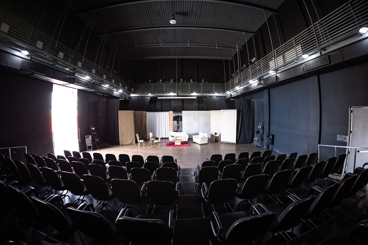 Show em homenagem a Vander Lee movimenta o Teatro Raul Belém Machado Vista interna da plateia e do palco do Teatro Raul Belém Machado, com fileiras de poltronas pretas em primeiro plano e um cenário montado ao fundo com sofás e divisórias.