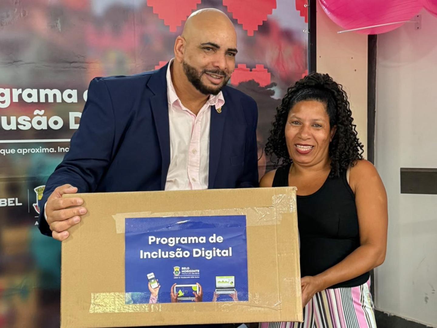 Mutirão de entrega de computadores recondicionados beneficia 143 famílias da Regional Norte de BH Um homem e uma mulher ladeados, em que ele entrega uma caixa contendo computador à ela, ambos com semblantes sorridentes
