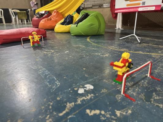 #pratodosverem: robôs da DHEL Robótica, que trouxe o Futebol de Robôs para o UAI FIC. Os brinquedos são amarelos, vermelhos e verdes e estão à frente de puffs coloridos ao fundo.