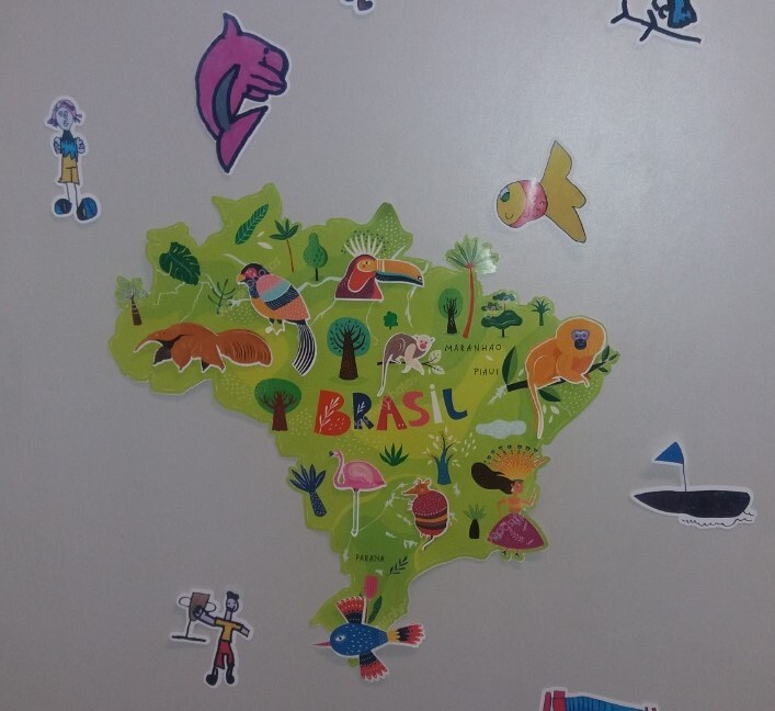 Fotografia do mapa do brasil desenhado na cor verde, com animais e árvores da fauna e flora brasileira. Ao redor, desenhos de pessoas e de animais da fauna brasileira.