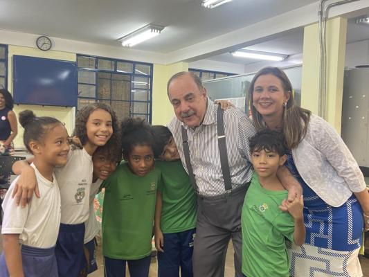 #paratodosverem: fotografia colorida do prefeito de Belo Horizonte, Fuad Noman, e da secretária de educação, Roberta Martins, ao lado de seis alunos da Escola Municipal Edson Pisani. Todos estão centralizados na foto, passando os braços por cima do ombro uns dos outros. Os(As) estudantes, quatro meninas e dois meninos, utilizam camisas verdes e brancas sorriem alegremente para a foto. Foto por: João Pedro Ribeiro