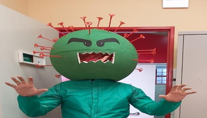  #paratodosverem Descrição: Fotografia de uma pessoa fantasiada representando um vírus, usando uma máscara em formato circular verde, com as roupas também em tom de verde. Foto por: Acervo Emei Vila Leonina