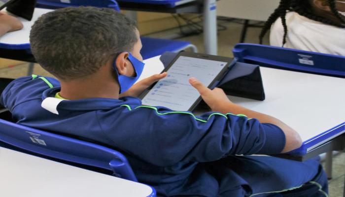 #paratodosverem Descrição: fotografia colorida com um estudante usando uniforme em cor azul, utilizando um tablet. Foto: Pedro Oliveira 
