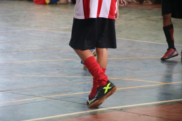 #paratodosverem Descrição: fotografia colorida de uma pessoa usando roupas para a prática de futsal enquanto a atividade é realizada em uma quadra. Foto por: Luiz Fernando Afonso Veloso.