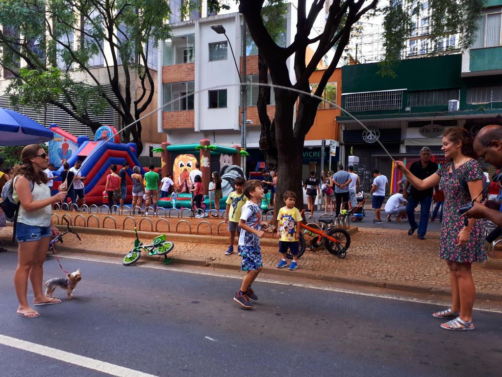 Criança pula corda na rua com ajuda de adultos