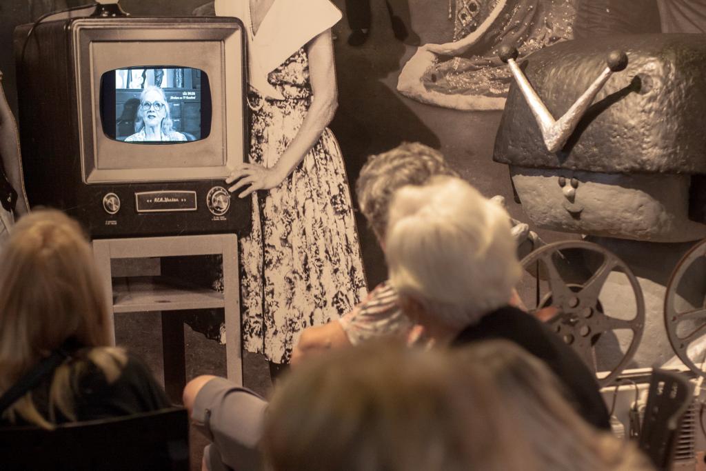 Pessoas assistem filme antigo no museu