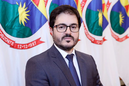 Homem branco de barba e cabelos escuros veste terno azul marinho