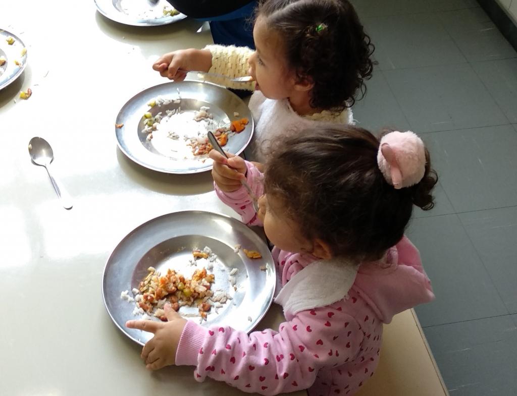 Crianças se alimentam sentadas em mesa na escola