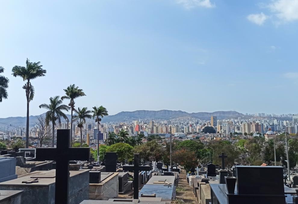 PBH abre concessão para uso perpétuo de novos jazigos nos cemitérios do Bonfim, da Paz, da Consolação e da Saudade A imagem mostra uma vista panorâmica do Cemitério do Bonfim. Em primeiro plano estão túmulos e jazigos de pedra dispostos em fileiras. Destacam-se duas grandes cruzes pretas instaladas sobre os túmulos mais próximos. Ao fundo, na linha do horizonte, estãi prédios do centro de BH e, mais adiante, a Serra do Curral, sob um céu azul claro com poucas nuvens
