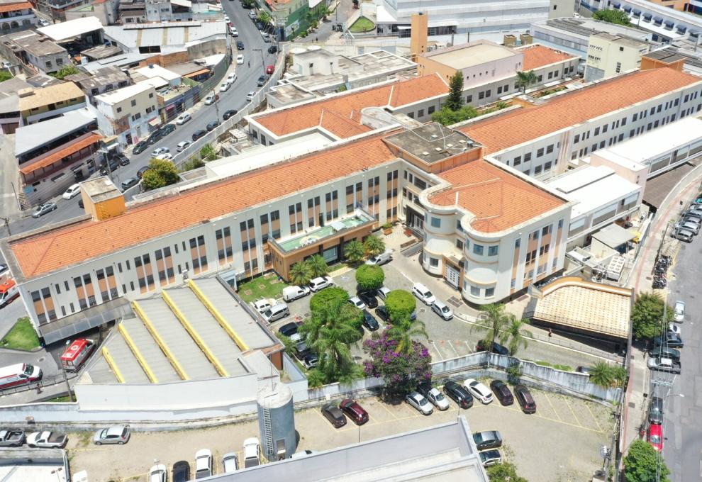 Programa de Ofertas de Cuidado Integrado agiliza atendimento no Hospital Odilon Behrens, que projeta triplicar o acesso a diagnósticos mais rápidos Foto aérea do Hospital Metropolitano Odilon Behrens. Na imagem há carros estacionados, canteiros com árvores de flores roxas e área de acesso com ambulâncias.