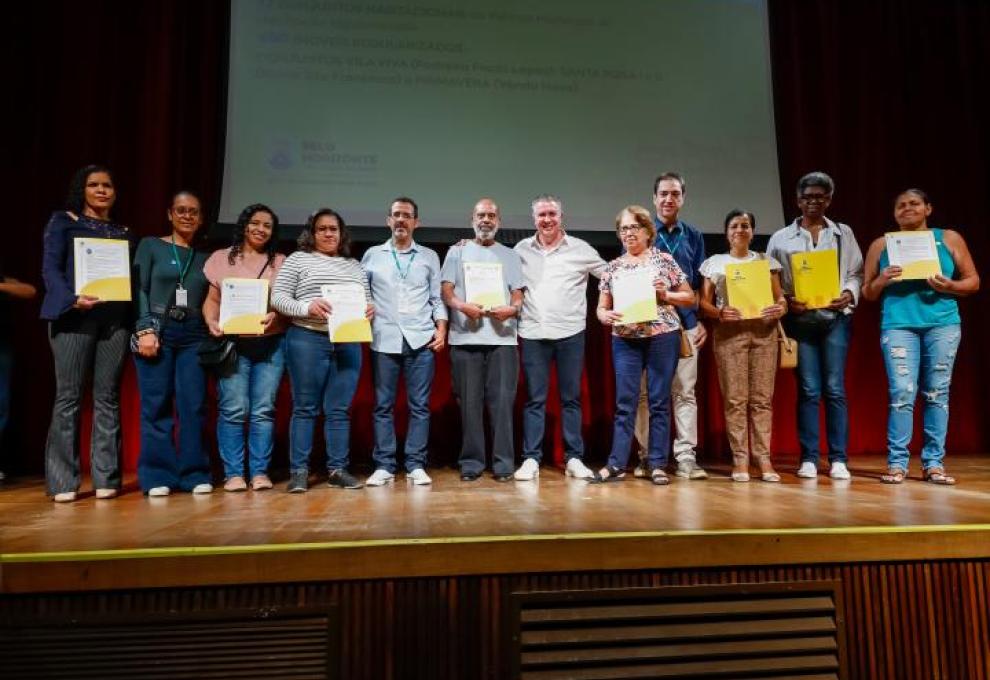 Prefeito Álvaro Damião e presidente da Urbel estão ao lado de oito moradores de vilas e favelas que receberam títulos de regularização fundiária.