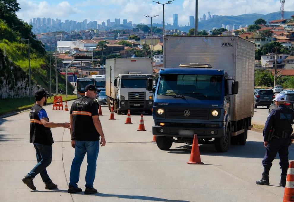 Fiscais da PBH com coletes pretos fiscalizam caminhões em via de Belo Horizonte