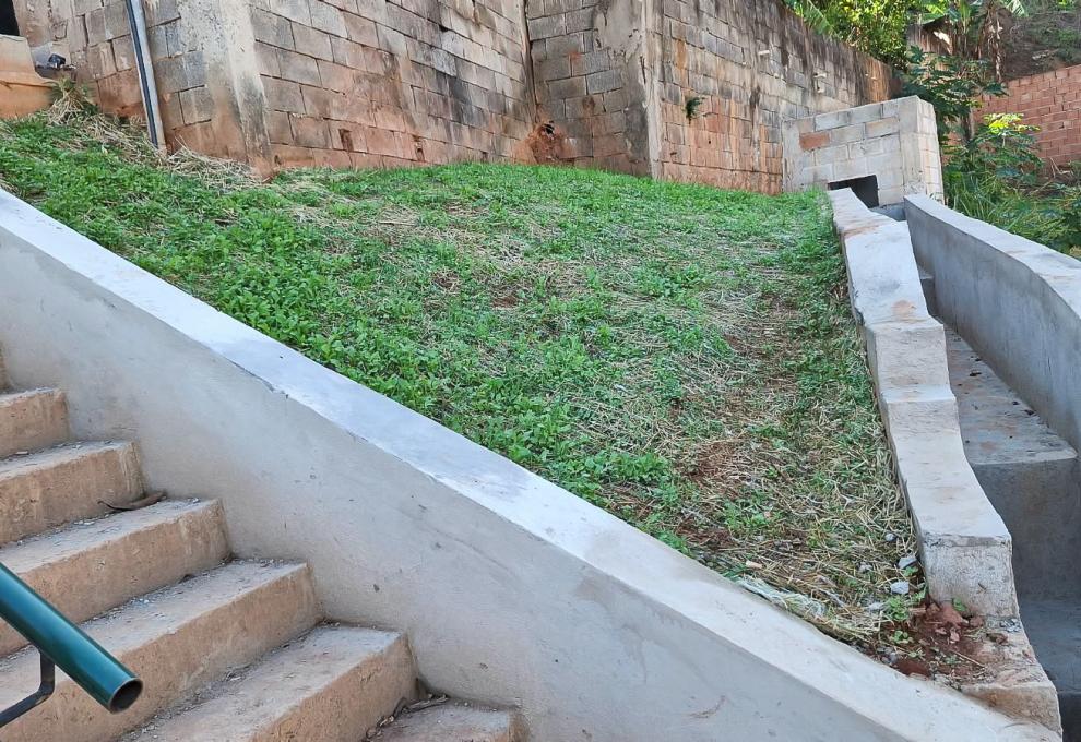 Prefeitura de BH finaliza mais uma obra de contenção de encosta para eliminar risco geológico e dar mais segurança à população Imagem de estrutura de concreto construída para escoamento de água de chuva e parte gramada pra conter erosão