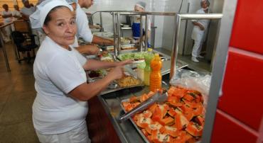 Servidora do Restaurante Popular serve frutas