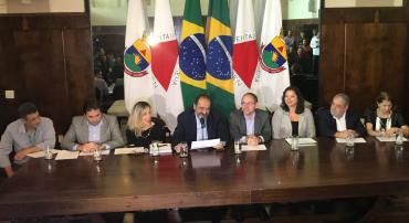 O prefeito de Belo Horizonte, Alexandre Kalil, e outros seis secretários sentados em mesa no Salão Nobre da Prefeitura de Belo Horizonte.
