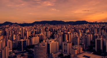 Prédios de Belo Horizonte com Serra do Curral e horizonte ao fundo, foto em sépia avermelhado.