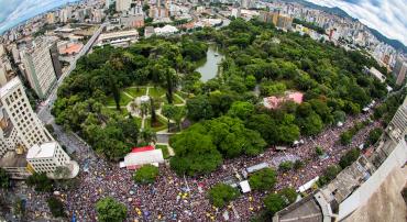 Uma multidão de foliões toma conta da avenida Afonso Pena, na altura do Parque Municipal Américo Renneé Giannetti. Foto aérea mosta multidão, parque municipal, prédios e horizonte.