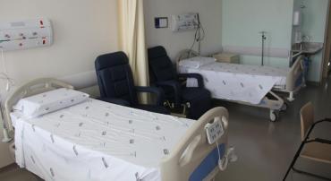 Quarto do Hospital do Barreiro com dois leitos, duas poltronas, pia e cadeiras.
