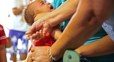 Criança no colo é vacinada e chora