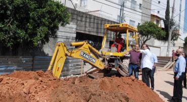 Prefeito Alexandre Kalil está ao lado de engenheiros da prefeitura próximo a obras e a um trator na rua Genoveva de Souza