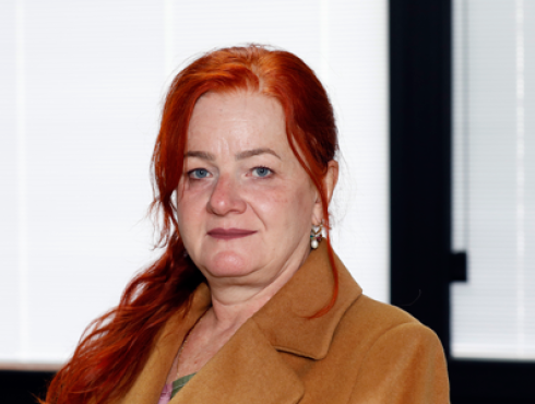 Mulher branca de cabelos longos ruivos e lisos veste casaco marrom claro