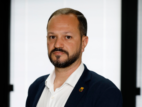 Homem branco com barba e cabelos escuros veste terno azul marinho