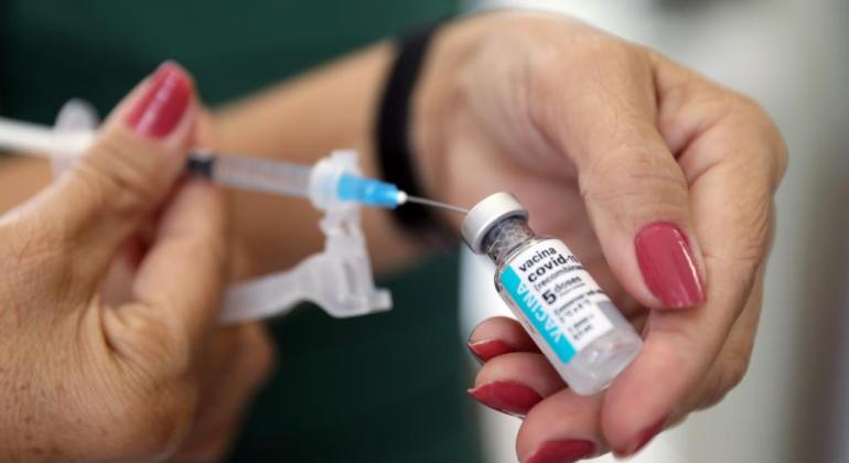 Imagem de enfermeira com frasco de vacina contra a Covid-19