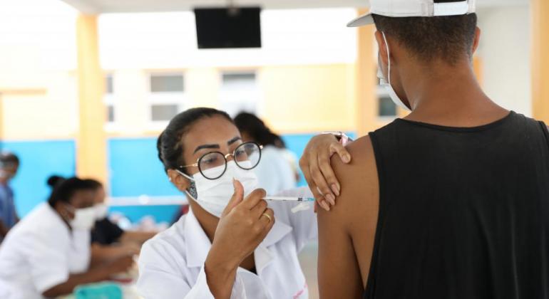 PBH convoca novas faixas etárias para receberem a dose de reforço contra a Covid Profissional aplica vacina contra a Covid em morador de Belo Horizonte