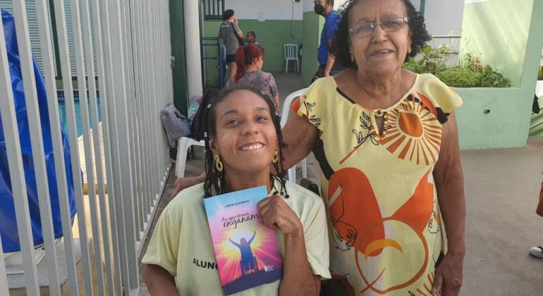 Lupercia Borges, cadeirante com paralisia cerebral, autora do livro As aparências enganam. Ao lado, em pé, sua mãe.