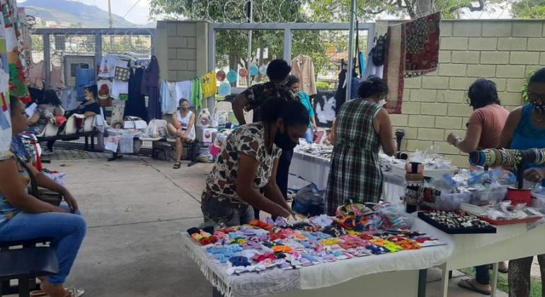 Bazar comercializa produtos de projeto de enfrentamento à violência doméstica Pessoas comprando coisas no bazar