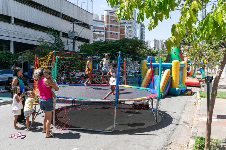 Crianças brincam em brinquedos infláveis e cama elástica durante atividade do programa A Rua é Nossa, em Belo Horizonte.