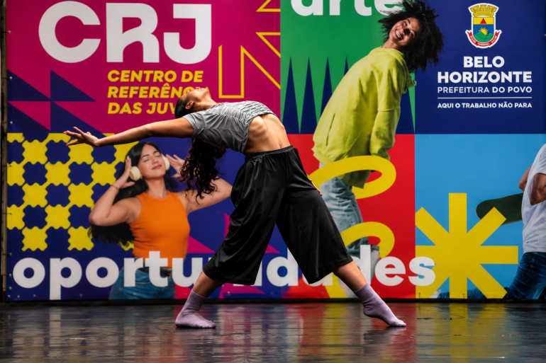Jovem realiza movimento de dança em frente a painel colorido do Centro de Referência das Juventudes (CRJ), em Belo Horizonte.