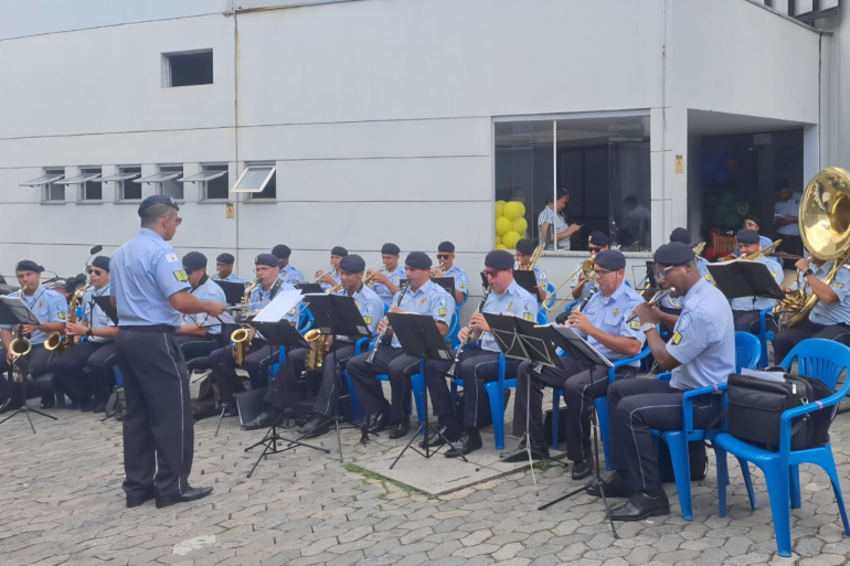 Banda da Guarda Municipal se apresenta nesta sexta-feira (17) na Praça Sete integrantes da guarda municipal sentados em cadeiras azuis se apresentam ao público durante evento