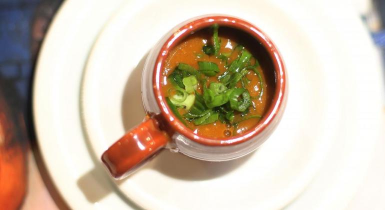 Caneca com caldo de feijão e tempero verde. 