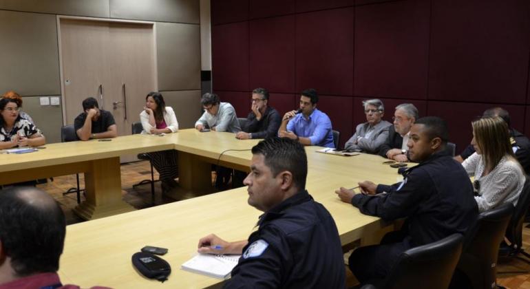 Diretor de Eventos da Belotur, Gilberto Castro fala para Grupo de Trabalho do Carnaval 2019, sentados em sala com mesa em forma de "u". Foto mostra dose pessoas no evento.