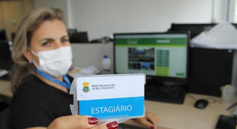 Prefeitura abre 300 vagas de estágio, com salários que chegam a R$ 1.114 Estagiária mostra o crachá para a câmera