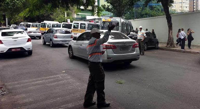 Agente de trânsito sinaliza para carros, nas ruas. 