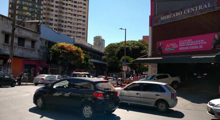 Dois carros transitam em avenida Augusto de Lima, em frente ao Mercado Central, durante o dia. 
