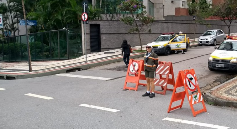 Cruzamento de rua com agentes da BHTrans e sinais de rua interditada, durante o dia. 